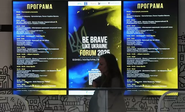 A woman stands near a poster in support of Ukraine, in Warsaw, Poland, Saturday, May 10, 2025. (AP Photo/Czarek Sokolowski)