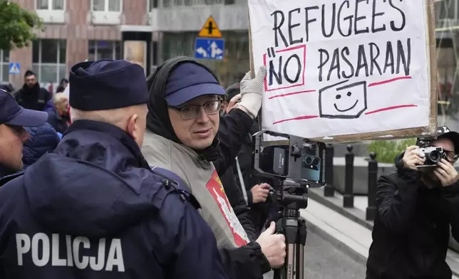 A man holds a poster that says "Refugees NO pasaran" in Warsaw, Poland, Saturday, May 10, 2025. (AP Photo/Czarek Sokolowski)