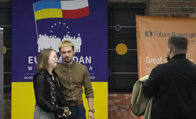Two people stand near a poster for a forum devoted to Polish-Ukrainian solidarity in Warsaw, Poland, Saturday, May 10, 2025. (AP Photo/Czarek Sokolowski)