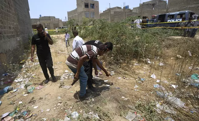 Pakistani investigators examine at a cordoned off site, where Pakistan's air defense system shot down a suspected Indian drone, in Karachi, Pakistan, Thursday, May 8, 2025. (AP Photo/Fareed Khan)