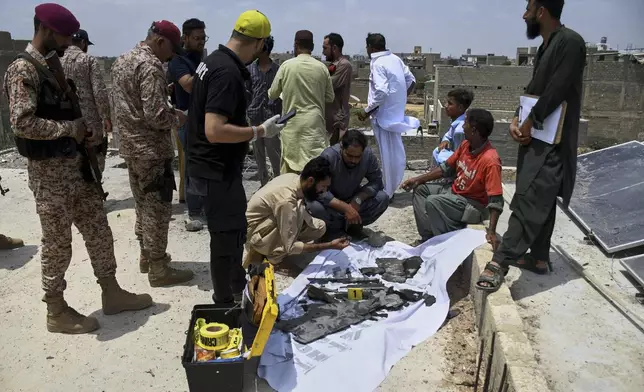 Paramilitary soldiers stand guard as investigators collect pieces of a suspected Indian drone at the site of a drone crash in Karachi, Pakistan, Thursday, May 8, 2025. (AP Photo/Fareed Khan)