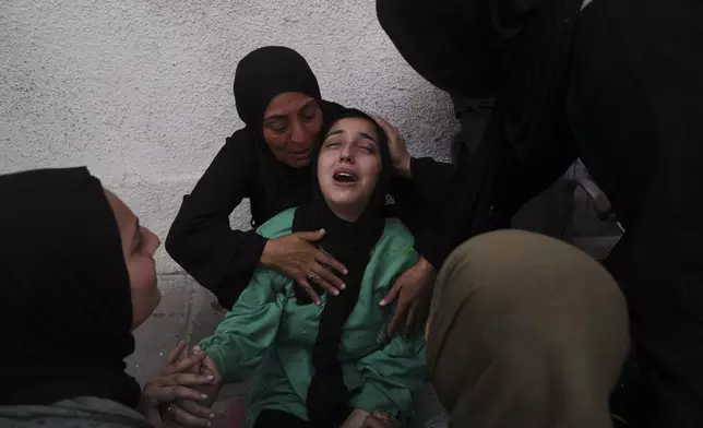 Walaa Al-Kilani, center, mourns her mother and brother, who were killed when an Israeli military strike hit a school sheltering displaced residents, at Al-Shifa Hospital in Gaza City, Monday, May 26, 2025. (AP Photo/Jehad Alshrafi)
