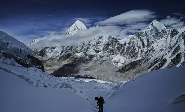 Mount Pumori, center left, looms in the background as a mountaineer negotiates Khumbu Icefall to descend to Everest Base Camp, in Nepal, May 4, 2025. (AP Photo/Pasang Rinzee Sherpa)