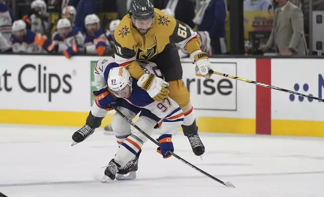 Vegas Golden Knights right wing Mark Stone (61) falls over Edmonton Oilers center Connor McDavid (97) during overtime of Game 2 of a second-round NHL hockey playoff series Thursday, May 8, 2025, in Las Vegas. (AP Photo/John Locher)