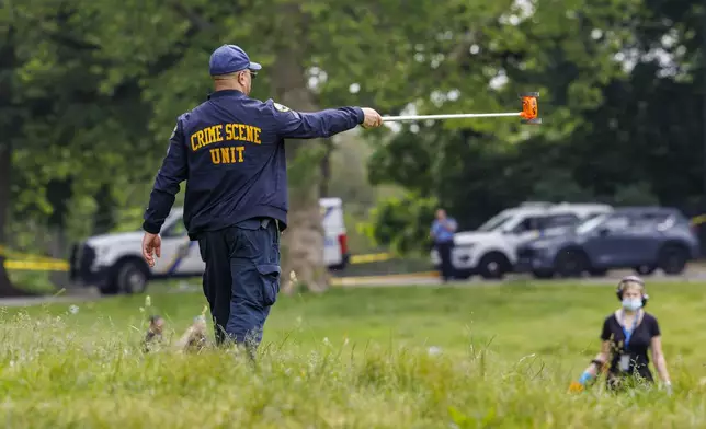 Philadelphia police Crime Scene Unit officer directs the search of people using metal detectors to search the area around the mass shooting on Lemon Hill, Tuesday, May 27, 2025. (Alejandro A Alvarez/The Philadelphia Inquirer via AP)