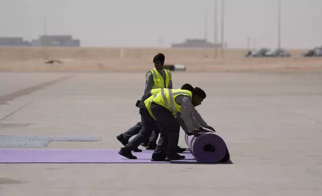 Workers roll the red carpet as President Donald Trump arrives on Air Force One at King Khalid International Airport Royal Terminal in Riyadh, Saudi Arabia, Tuesday, May 13, 2025 . (AP Photo/Alex Brandon)