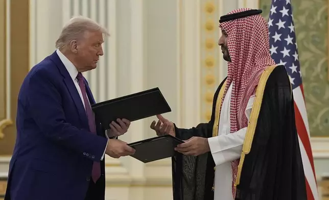 President Donald Trump and Saudi Crown Prince Mohammed bin Salman exchange documents during a signing ceremony at the Royal Palace, Tuesday, May 13, 2025. (AP Photo/Alex Brandon)