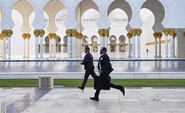 Secret Service men run during a tour by President Donald Trump and UAE President Mohammed bin Zayed Al Nahyan at the Sheikh Zayed Grand Mosque, Thursday, May 15, 2025, in Abu Dhabi, United Arab Emirates. (AP Photo/Alex Brandon)