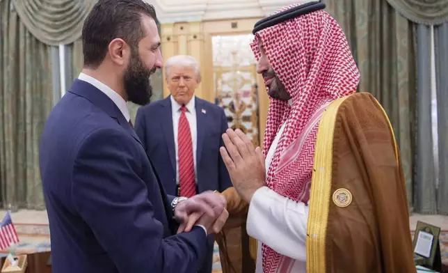 In this photo released by the Saudi Royal Palace, President Donald Trump, centre, looks to Saudi's Crown Prince Mohammed bin Salman, right, shake hands with Syria's interim President Ahmad al-Sharaa, in Riyadh, Saudi Arabia, Wednesday, May 14, 2025. (Bandar Aljaloud/Saudi Royal Palace via AP)