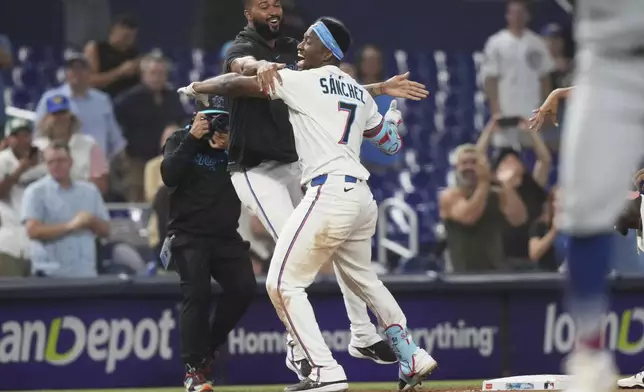 Miami Marlins' Jesus Sanchez (7) celebrates with Sandy Alcantara, left, after hitting a walk-off triple in the ninth inning to defeat the Chicago Cubs in a baseball game Monday, May 19, 2025, in Miami. (AP Photo/Lynne Sladky)