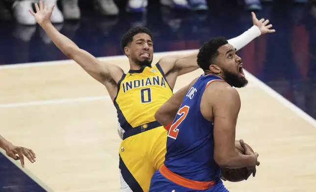 New York Knicks center Karl-Anthony Towns, right, drives to the basket against Indiana Pacers guard Tyrese Haliburton during the first half of Game 3 of the Eastern Conference finals of the NBA basketball playoffs Sunday, May 25, 2025, in Indianapolis. (AP Photo/Jeff Roberson)