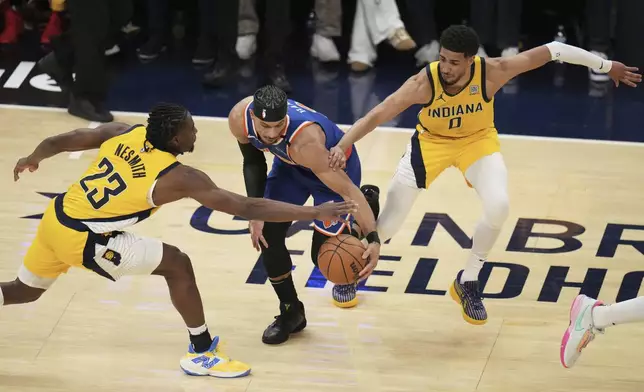 New York Knicks guard Josh Hart, middle, is defended by Indiana Pacers forward Aaron Nesmith (23) and guard Tyrese Haliburton (0) during the first half of Game 3 of the Eastern Conference finals of the NBA basketball playoffs Sunday, May 25, 2025, in Indianapolis. (AP Photo/Jeff Roberson)