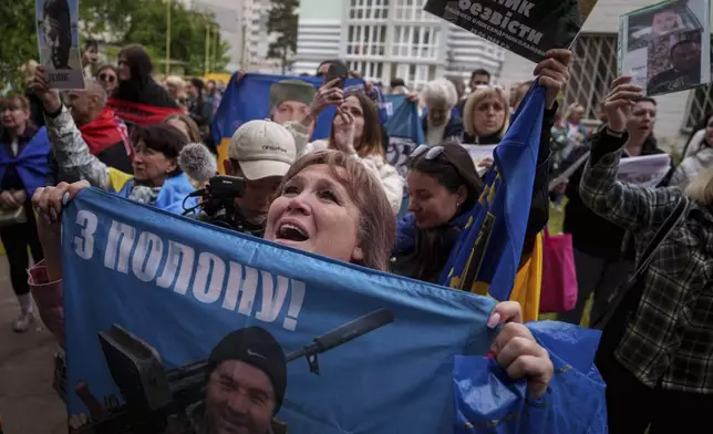Relatives of missing and imprisoned Ukrainian soldiers show photographs to servicemen returned from captivity in a POW exchange in Ukraine, Tuesday, May 6, 2025. (AP Photo/Evgeniy Maloletka)