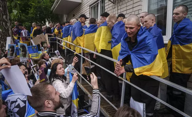 Relatives of missing and imprisoned Ukrainian soldiers show photographs to servicemen returned from captivity in a POW exchange in Ukraine, Tuesday, May 6, 2025. (AP Photo/Evgeniy Maloletka)