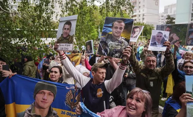 Relatives of missing and imprisoned Ukrainian soldiers show photographs to servicemen returned from captivity in a POW exchange in Ukraine, Tuesday, May 6, 2025. (AP Photo/Evgeniy Maloletka)