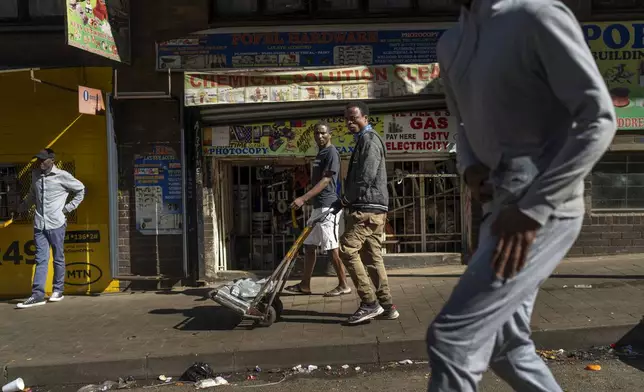 Residents watch the annual Hillbrow street parade organized by the Windybrow Arts Centre and other local organisations go by in downtown Johannesburg, South Africa, Saturday, May 24, 2025. (AP Photo/Jerome Delay)