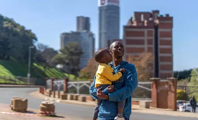Residents watch the annual Hillbrow street parade organized by the Windybrow Arts Centre and other local organisations go by in downtown Johannesburg, South Africa, Saturday, May 24, 2025. (AP Photo/Jerome Delay)