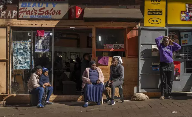 Residents watch the annual Hillbrow street parade organized by the Windybrow Arts Centre and other local organisations go by in downtown Johannesburg, South Africa, Saturday, May 24, 2025. (AP Photo/Jerome Delay)