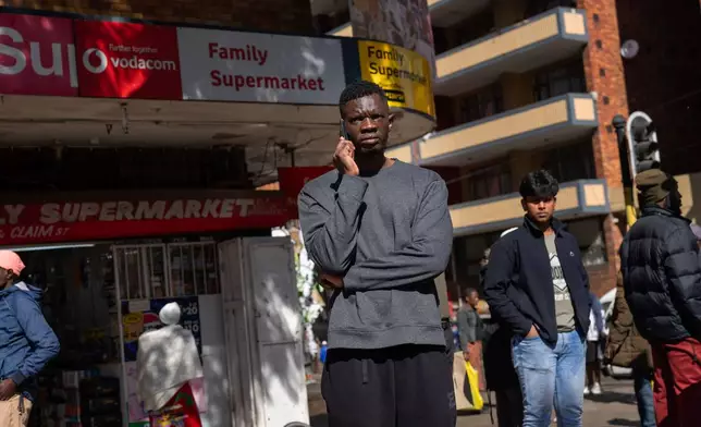 Residents watch the annual Hillbrow street parade organized by the Windybrow Arts Centre and other local organisations go by downtown Johannesburg, South Africa, Saturday, May 24, 2025. (AP Photo/Jerome Delay)