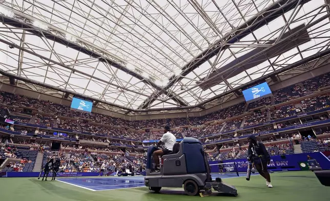 FILE - Court workers dry the playing surface at Arthur Ashe Stadium after a sudden downpour with the retractable roof open caused play to be delayed between Petra Kvitova, of the Czech Republic, and Jessica Pegula, of the United States, during the fourth round of the U.S. Open tennis championships, Monday, Sept. 5, 2022, in New York. (AP Photo/Julia Nikhinson, file)