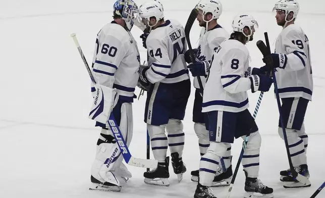 Toronto Maple Leafs goaltender Joseph Woll (60) is congratulated by his teammates after winning Game 6 of a second-round NHL hockey playoff series against the Florida Panthers, Friday, May 16, 2025, in Sunrise, Fla. (AP Photo/Lynne Sladky)