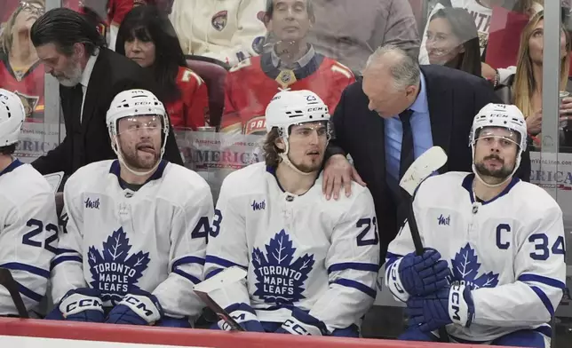 Toronto Maple Leafs head coach Craig Berube, rear, talks with left wing Matthew Knies (23) during the third period in Game 6 of a second-round NHL hockey playoff series against the Florida Panthers, Friday, May 16, 2025, in Sunrise, Fla. (AP Photo/Lynne Sladky)