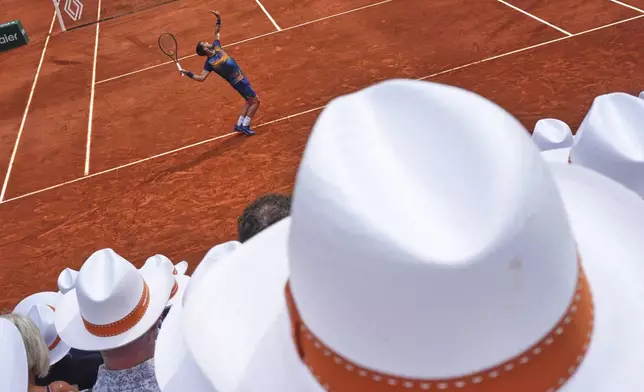 Bosnia and Herzegovina's Damir Dzumhur is backdropped by spectators' hats as he returns the ball to France's Giovanni Mpetshi Perricard, during their second round match of the French Tennis Open, at the Roland-Garros stadium, in Paris, Wednesday, May 28, 2025. (AP Photo/Lindsey Wasson)