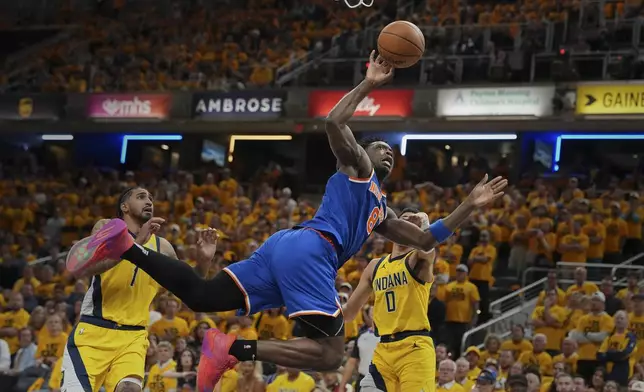 New York Knicks forward OG Anunoby (8) shoots the ball past Indiana Pacers forward Obi Toppin (1) and guard Tyrese Haliburton (0) during the second half of Game 4 of the Eastern Conference finals of the NBA basketball playoffs in Indianapolis, Tuesday, May 27, 2025. (AP Photo/Michael Conroy)
