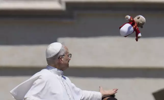 Pope Leo XIV catches a little doll representing the Pope while leaving on Papamobile after his weekly general audience in St. Peter's Square at The Vatican, Wednesday, May 28, 2025. (AP Photo/Gregorio Borgia)