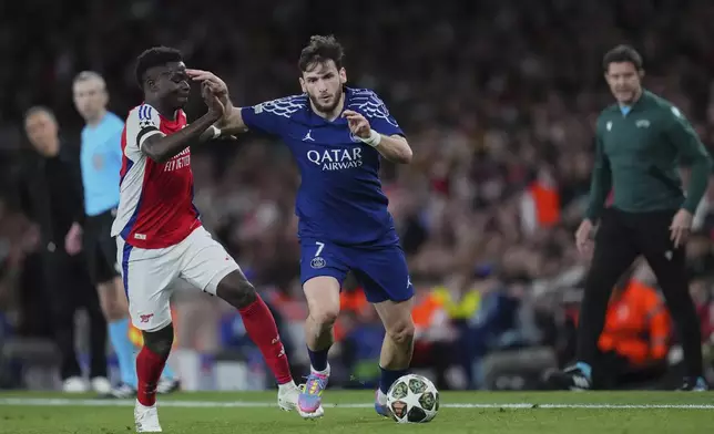 Arsenal's Bukayo Saka, left, fights for the ball with PSG's Khvicha Kvaratskhelia during the Champions League semifinal first leg soccer match between Arsenal and Paris Saint-Germain at Emirates Stadium in London, England, Tuesday, April 29, 2025. (AP Photo/Kirsty Wigglesworth)