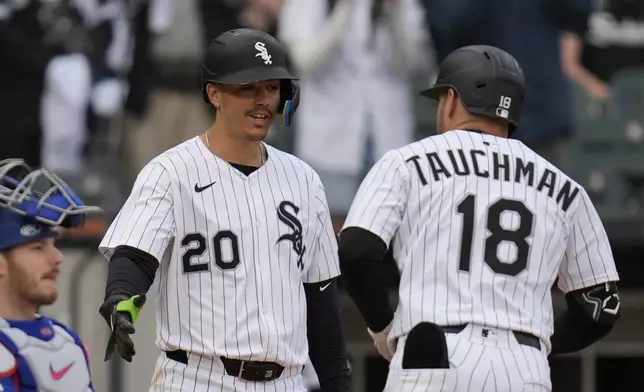 Chicago White Sox's Miguel Vargas (20), left, slaps hands with Mike Tauchman (18) after Tauchman hit a home run during the eighth inning of a baseball game against the Texas Rangers, Saturday, May 24, 2025, in Chicago. (AP Photo/Erin Hooley)