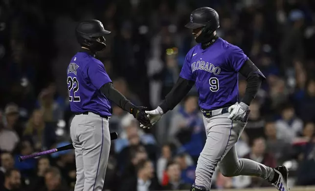 Colorado Rockies' Brenton Doyle (9) celebrates with teammate Mickey Moniak (22) after hitting a solo home run during the seventh inning of a baseball game against the Chicago Cubs Tuesday, May 27, 2025, in Chicago. (AP Photo/Paul Beaty)