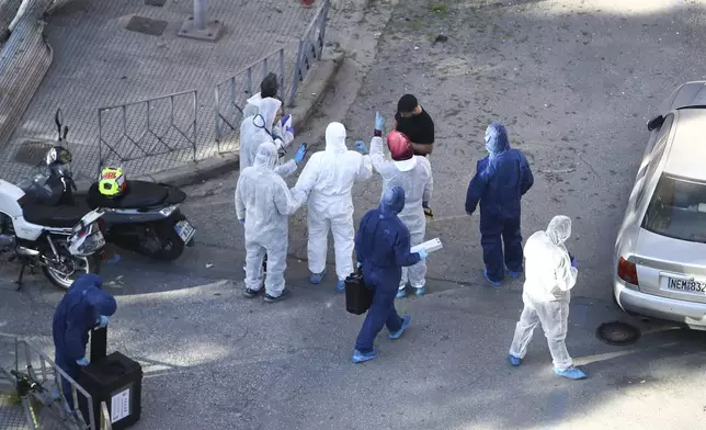 Greek police forensic experts search the area where a 38-year-old woman was killed early Saturday when a bomb she was carrying exploded in her hands outside a bank branch, local police said, in Thessaloniki, northern Greece, May 3, 2025. (AP Photo/Giannis Papanikos)