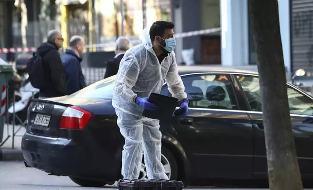 A Greek police forensic expert searches for evidence at the area where a 38-year-old woman was killed early Saturday when a bomb she was carrying exploded in her hands outside a bank branch, local police said, in Thessaloniki, northern Greece, May 3, 2025. (AP Photo/Giannis Papanikos)