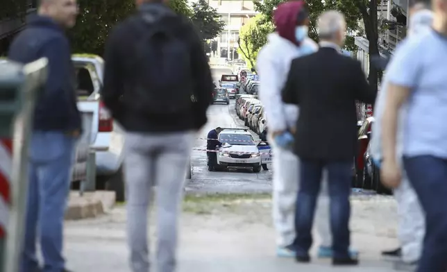 Greek policemen and forensic experts are seen at the area where a 38-year-old woman was killed early Saturday when a bomb she was carrying exploded in her hands outside a bank branch, local police said, in Thessaloniki, northern Greece, May 3, 2025. (AP Photo/Giannis Papanikos)