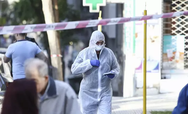A Greek police forensic expert searches for evidence at the area where a 38-year-old woman was killed early Saturday when a bomb she was carrying exploded in her hands outside a bank branch, local police said, in Thessaloniki, northern Greece, May 3, 2025. (AP Photo/Giannis Papanikos)