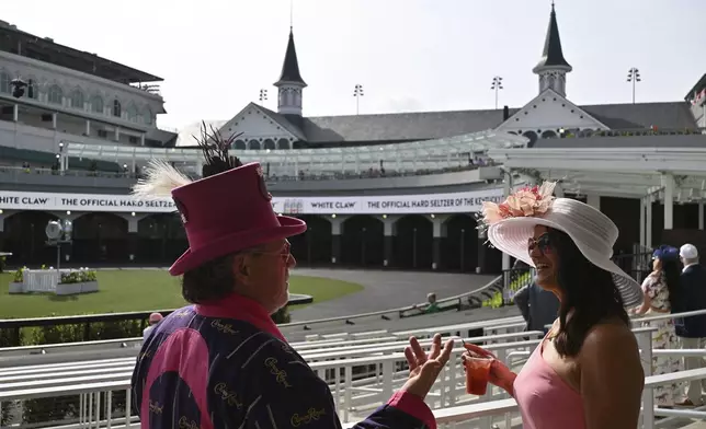 People chat as they stand around the paddock at Churchill Downs before the 151st running of the Kentucky Oaks horse race Friday, May 2, 2025, in Louisville, Ky. (AP Photo/Jon Cherry)