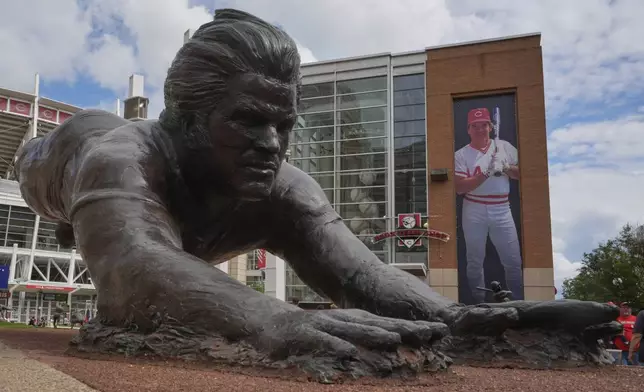 A bronze statue and a banner of former Cincinnati Reds player Pete Rose are seen outside the Great American Ball Park, Tuesday, May 13, 2025, in Cincinnati. (AP Photo/Carolyn Kaster)