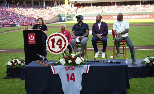 Pete Rose's daughter Fawn Rose speaks as Reds Hall of Fame players, left to right, George Foster, Barry Larkin and Eric Davis listen during Pete Rose Night events before a baseball game between the Cincinnati Reds and the Chicago White Sox, Wednesday, May 14, 2025, in Cincinnati. (AP Photo/Carolyn Kaster)