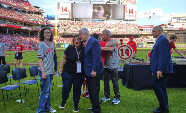 Cincinnati Reds owner Bob Castellini, right hugs Pete Rose's daughter Fawn Rose as they meet on the field for Pete Rose Night events before a baseball game between the Cincinnati Reds and the Chicago White Sox, Wednesday, May 14, 2025, in Cincinnati. (AP Photo/Carolyn Kaster)
