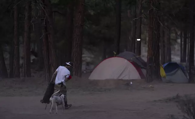 A person walks to a tent at a homeless encampment in Deschutes National Forest, Wednesday, April 30, 2025, near Bend, Ore. (AP Photo/Jenny Kane)