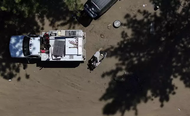 Chris Daggett, who lived in a homeless encampment in Deschutes National Forest, pushes a scooter belonging to another resident as he helps to remove items for fellow campers on Thursday, May 1, 2025, near Bend, Ore. (AP Photo/Jenny Kane)
