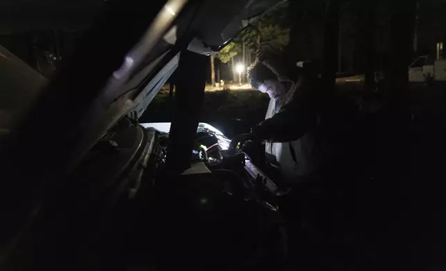 Greg Bishop works to get an RV to start at a homeless encampment in Deschutes National Forest Wednesday, April 30, 2025 near Bend, Ore. (AP Photo/Jenny Kane)