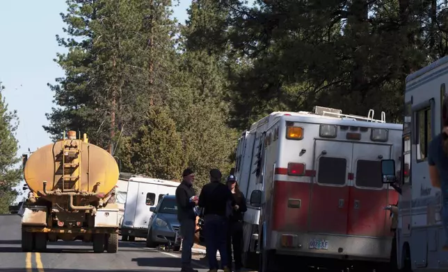 A trucking and logging vehicle, at left, drives past trailers lining China Hat Road as leaves an area that was closed off in Deschutes National Forest, Thursday, May 1, 2025 near Bend, Ore. (AP Photo/Jenny Kane)