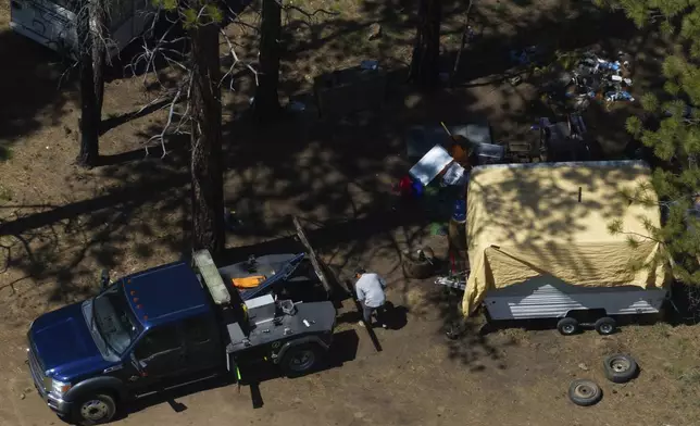 A tow truck driver helps removing a trailer for a person staying at a homeless encampment in Deschutes National Forest, Thursday, May 1, 2025, near Bend, Ore. (AP Photo/Jenny Kane)