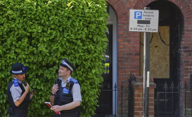 Police Community Support Officers stand near the fire damaged doorway of a house belonging to British Prime Minister Keir Starmer in Kentish Town in London, Tuesday, May 13, 2025. (AP Photo/Kirsty Wigglesworth)