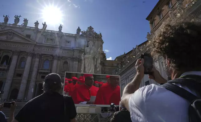 Faithful watch a giant screen showing images of cardinals entering the conclave, in St. Peter's Square at the Vatican, Wednesday, May 7, 2025. (AP Photo/Andrew Medichini)