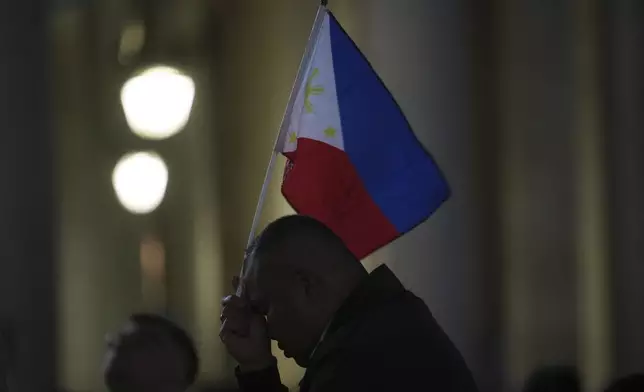 A pilgrim holds a flag of the Philippines in St Peter's Square during the cardinals' conclave to elect a new pope, at the Vatican, Wednesday, May 7, 2025. (AP Photo/Alessandra Tarantino)