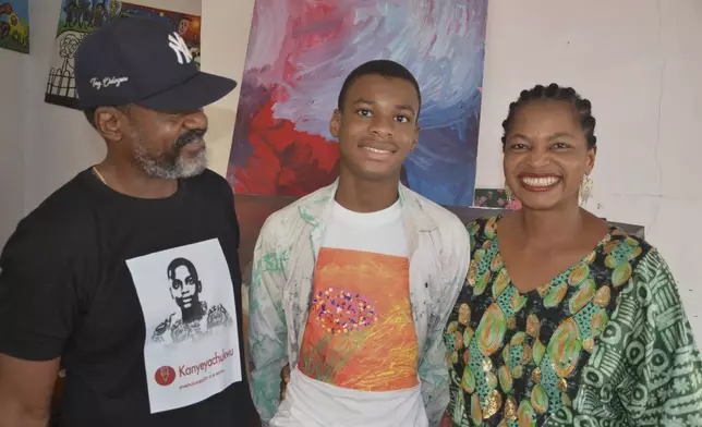 Kanyeyachukwu Tagbo Okeke, a 15 year-old autistic Nigerian, who set a Guinness World Record for the world's largest art canvas, is photograph with his parents in Abuja, Nigeria, Friday, April 18, 2025. (AP Photo/Olamikan Gbemiga)