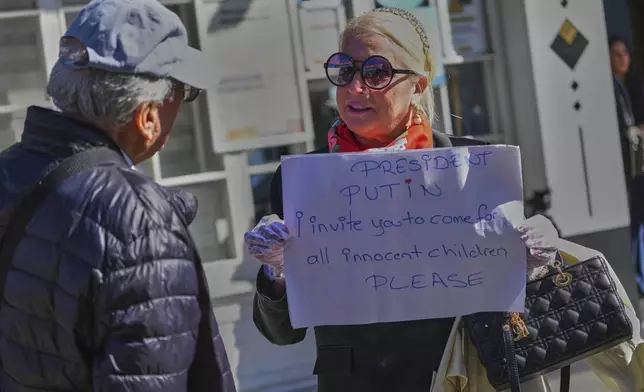 Ayse Sahil, whose family emigrated from Bolshevik in Russia, holds a board near Dolmabahce palace where talks between Russian and Ukrainian delegations are expected, in Istanbul, Turkey, Thursday, May 15, 2025. (AP Photo/Dilara Acikgoz)